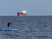 Scott paddleboarding by a ship