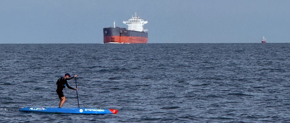 Scott paddleboarding by a ship